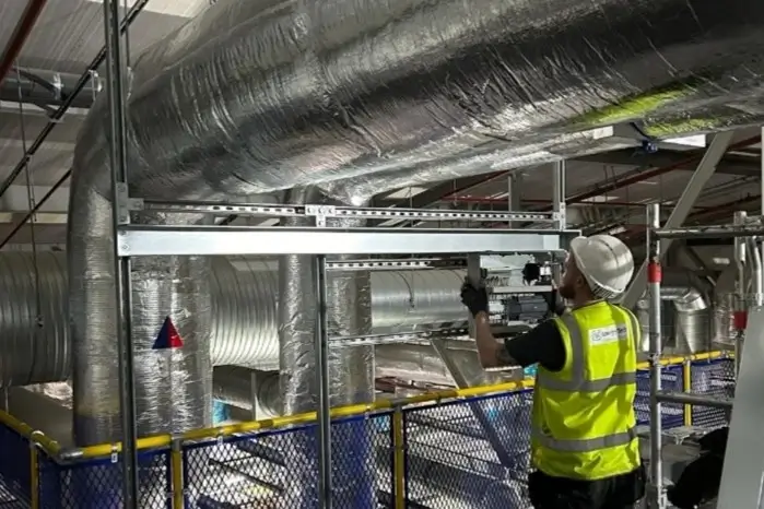 A man in a yellow vest is repairing a large pipe
