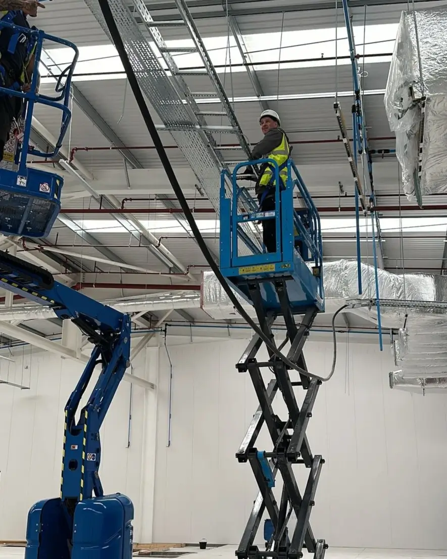 Two men working on a lift inside an industrial building
